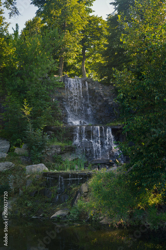 Scenic waterfall cascading over rocky cliff into tranquil pond.