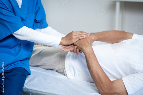 Fotografía Nurse gently holding a patient’s hands while sitting beside a hospital bed, care