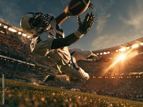 Football player diving to catch ball in stadium
