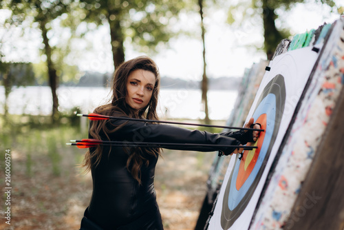 фотографія Woman collecting arrows from archery target board