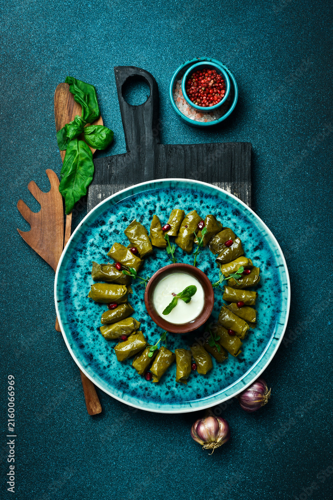 Fototapeta premium Traditional delicious Turkish foods: dolma (sarma) stuffed grape leaves rice. Close up. On a dark background.