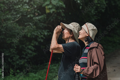 Фотография Side view of Asian couple standing close together, looking up to watch nature th