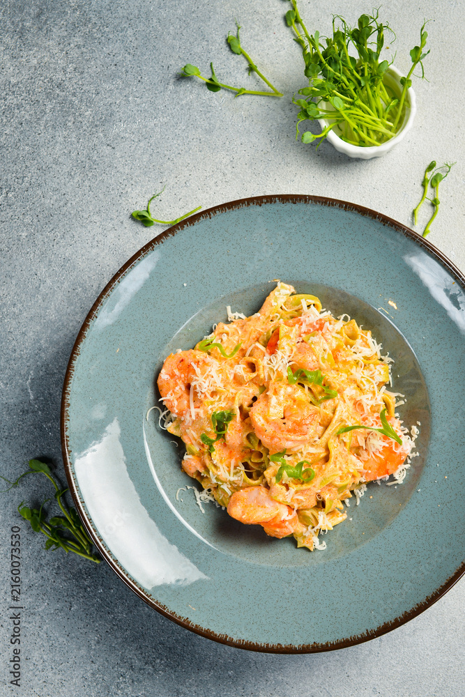 Naklejka premium Italian pasta with shrimp and parmesan cheese. In a plate. Restaurant dish. Close up.