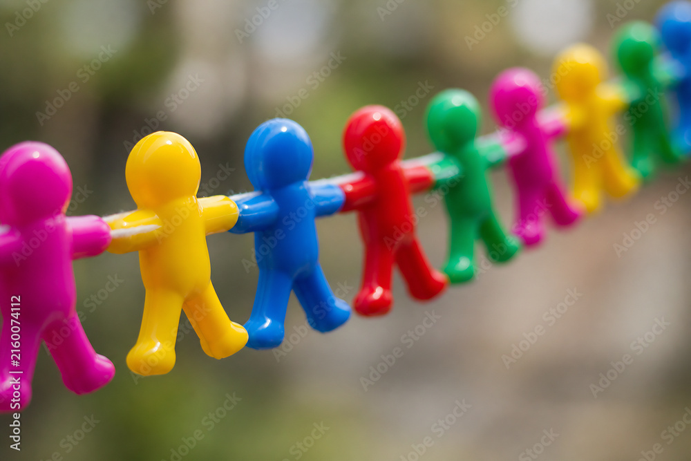 Obraz premium A line of colorful plastic figures are strung up against a blurred outdoor background.