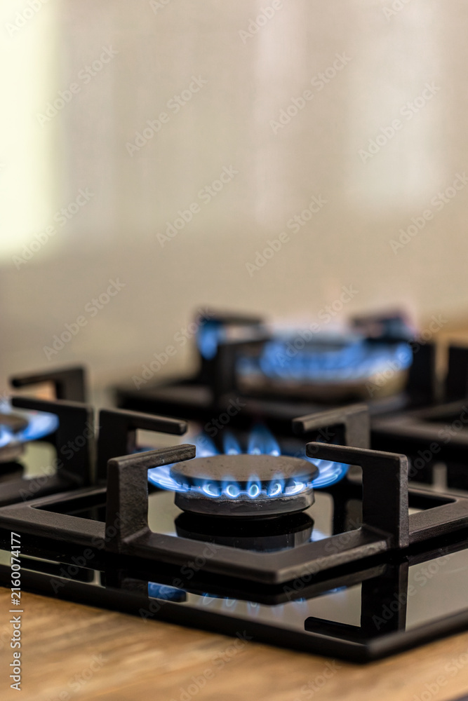 Naklejka premium Gas stove burner with blue flame. Vertical kitchen appliance detail with copy space.