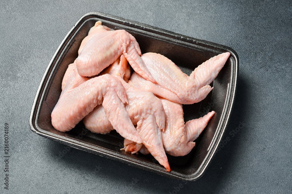 Fototapeta premium Fresh meat. Set of raw chicken wings. Meat on a plastic black container from the market. Close-up.