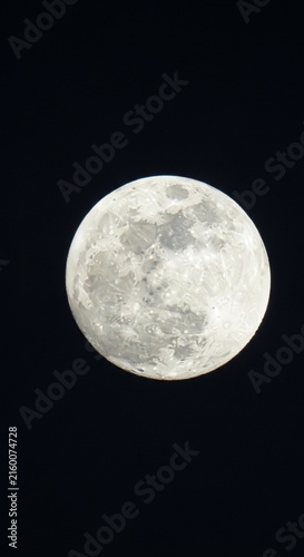Bright white moon glowing in a dark and clear night sky