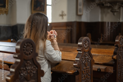 A woman prays inside a European Catholic church during Holy Mass, showing devotion and faith in a quiet moment of worship.