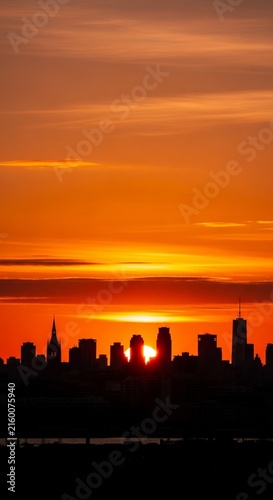Brilliant orange sky above a dark silhouetted city skyline at sunset