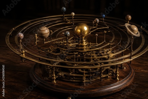 Brass orrery model of the solar system on a wooden desk