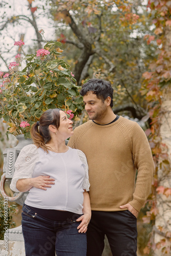 Foto Young couple sharing a tender moment during late‑term pregnancy in an autumn garden, expressing love, anticipation and family growth surrounded by warm seasonal colors