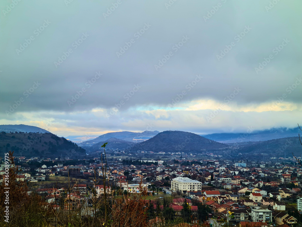 Fototapeta premium Town view surrounded by hills under cloudy sky