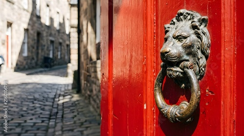 Antique bronze lion door knocker on a bright red wooden door in a city