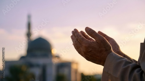 Person making dua prayer with mosque in background.