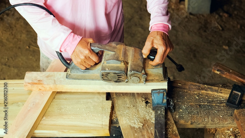 Obraz na plátne Close-up of a carpenter's hands operating an electric hand planer to shave and s