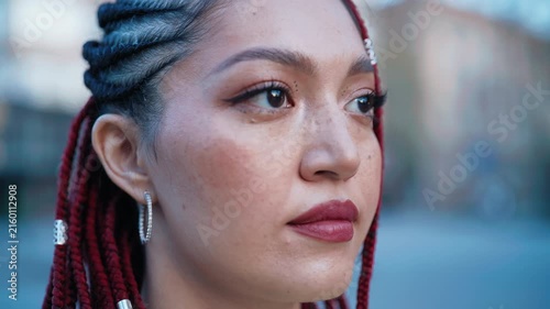 Portrait of a woman with red braids and freckles in an urban outdoor setting