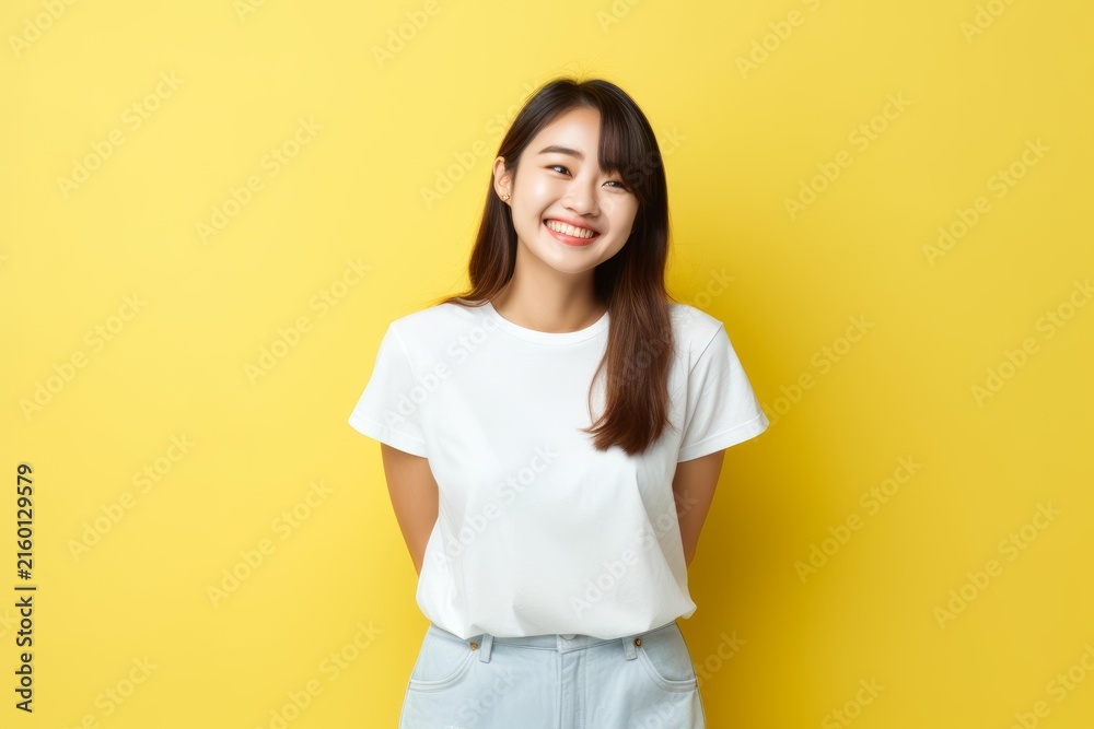 Obraz premium Happy young woman standing against yellow studio background, looking cheerful
