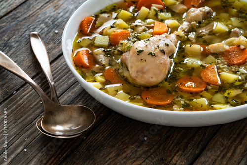 Krupnik - polish barley soup with chicken meat on wooden table
