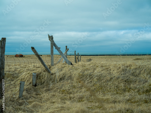 Weathered fence in rural Iceland under dramatic cloudy sky