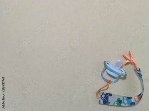 Foto Minimalist overhead flat lay of a baby pacifier with a car pattern pacifier clip on a clean kraft paperboard background with generous copy space
