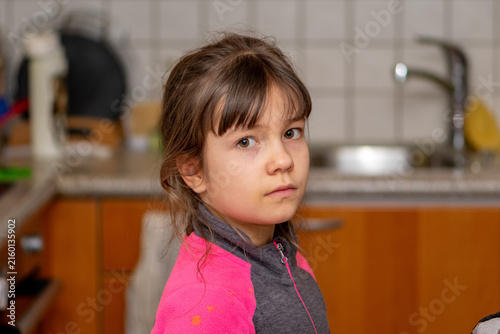 Canvas Print Serious young girl turning back and looking at camera indoors