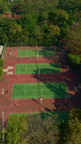 Vertical aerial view of tennis courts surrounded by urban greenery