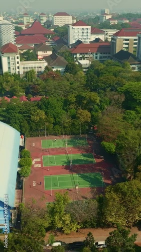 Partially hidden tennis courts surrounded by dense green trees from above