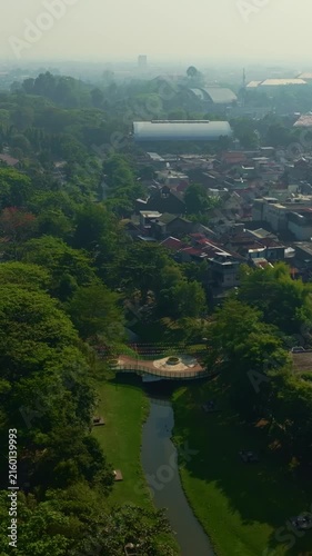 Hazy aerial panorama of green city park and winding canal