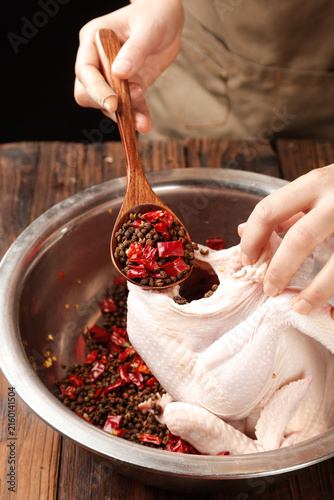 Fotografie Chef seasoning raw chicken with spicy peppercorns and red chilies in kitchen bow