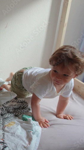 Fotografie Young child climbing out of bed without assistance in home bedroom, highlighting