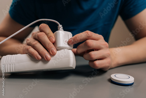 Cropped shot of person plugging a smart plug into a power strip and pressing its button, illustrating easy setup, remote control, energy saving home automation in a modern indoor setting.