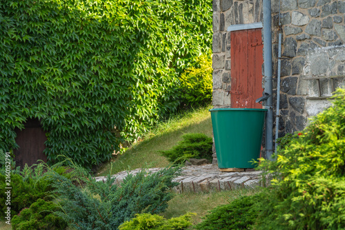 Rain Barrel in lush garden for eco friendly rainwater collection, storage and sustainable garden irrigation
