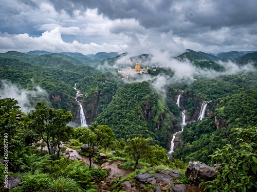 Breathtaking aerial view of winding ghat roads on lush green misty mountains leading to a sacred temple, hyper-realistic digital landscape