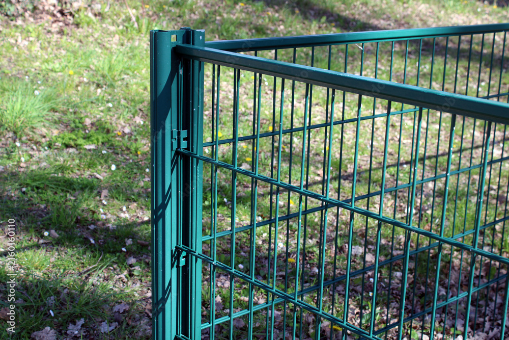 Fototapeta Clôture en panneaux de grillage rigide à double fil de couleur verte, installée sur des poteaux métalliques pour délimiter un espace extérieur.