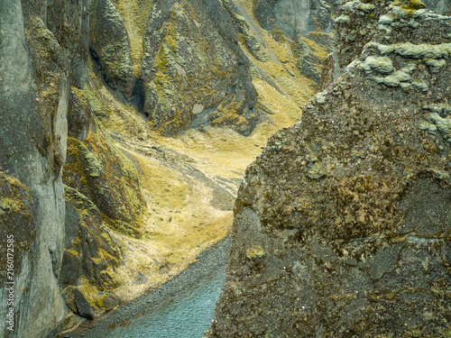Narrow river winding through moss-covered volcanic canyon in Iceland