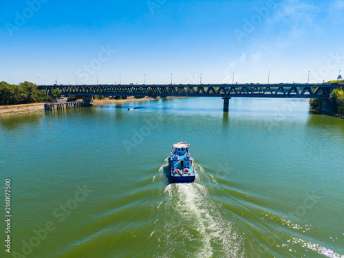 Foto River boat travels under a bridge on a clear day while leaving a wake in the wat
