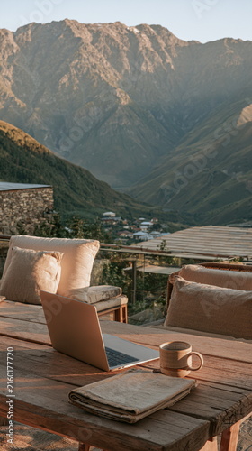 Warm hill view from a quiet porch, with soft chairs, stone walls, green peaks, and a calm dusk glow for cozy home, travel, and slow life ideas in air.