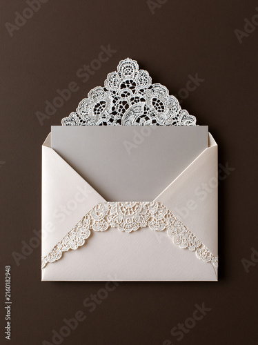Elegant Invitation with Lace Detail: A delicate cream envelope with intricate white lace trim holds a sophisticated grey insert card, perfect for wedding or special occasion invitations.