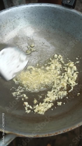 Cooking Thai stir-fried eggplant with pork (Phad Makheua Yao). Blanching green eggplants in oil, sautéing minced garlic and sliced pork, tossing blanched eggplants with seasonings