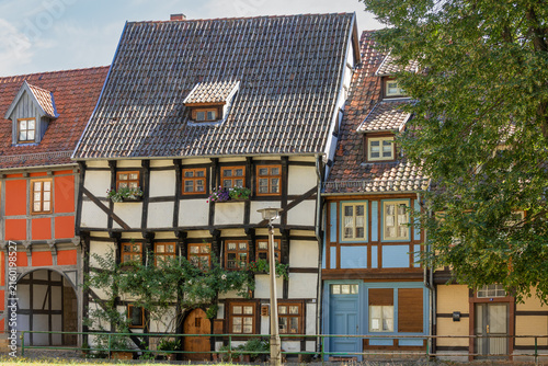 Obraz na plátne Charming, old-fashioned half-timbered cottage with potted plants, window boxes, and a blue-painted shopfront in Quedlinburg, Germany