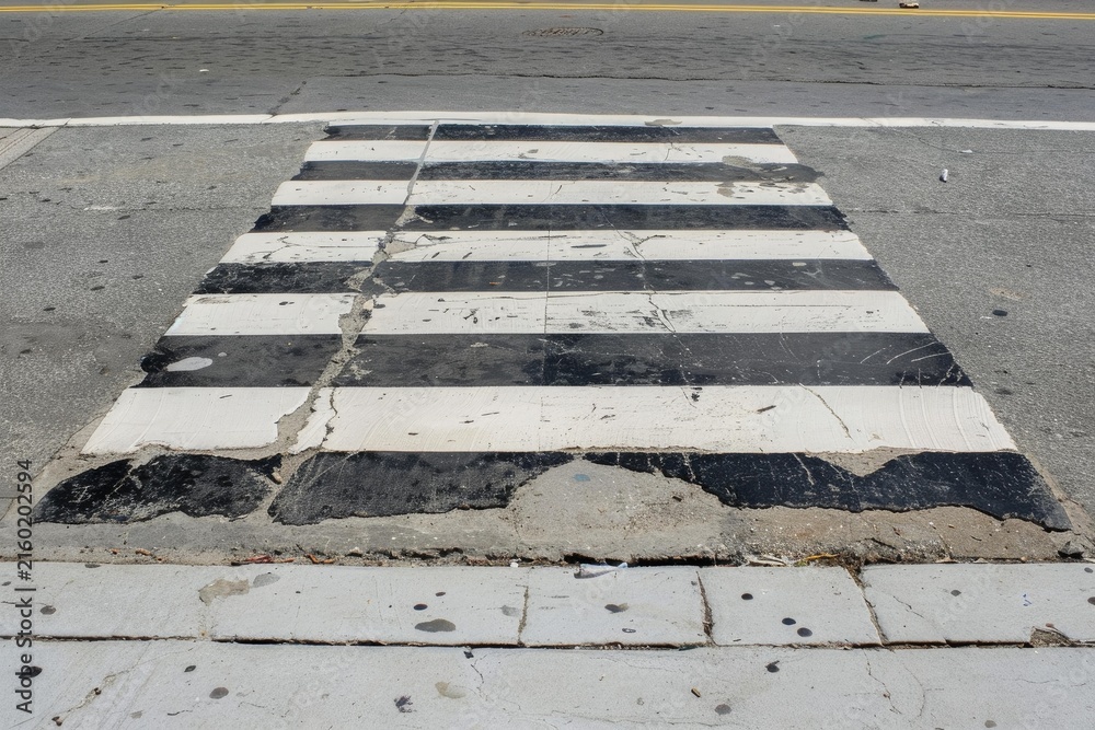 Fototapeta premium Deteriorated crosswalk painting showing urban decay and lack of maintenance creating unsafe conditions for pedestrians