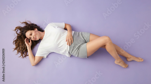 Top view of woman lying on her side relaxing on a purple background