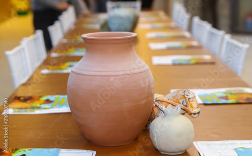 traditional horse sculpture arranged on a wooden table in an art studio workshop setting during a pottery craft masterclass for kids . Handmade terracotta clay vase, ceramic pomegranate, and