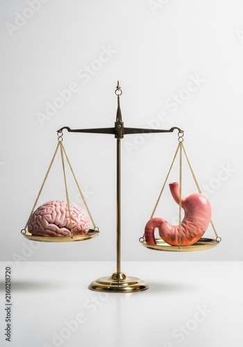 Human brain and stomach on golden balance scale. Conceptual comparison between mental focus and gut feeling. Scientific metaphor for weight of decision, digestion and neuroscience.