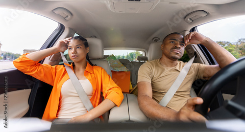 Obraz na płótnie Tired young African American couple sitting in car with tense expressions, both