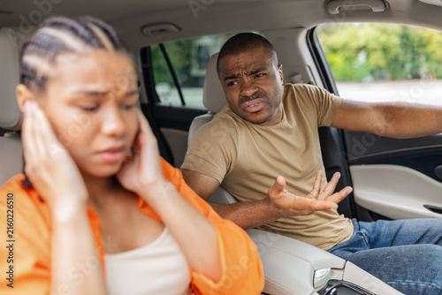 Quadro su tela Young African American couple arguing inside car, frustrated man gesturing angri