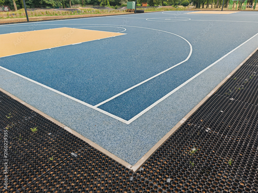 Fototapeta premium New outdoor basketball court with a artificial playground and sports flooring. Polymeric Rubber Surfacing called tartan flooring
