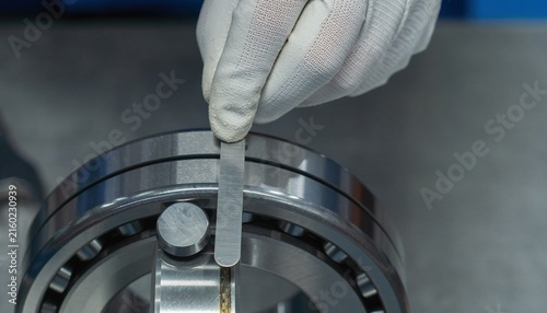 Technician using a feeler gauge to measure the clearance of a large industrial ball bearing.