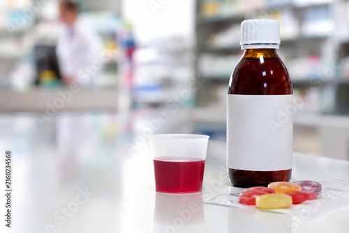 Botella de jarabe yvasos de medicinas en una farmacia