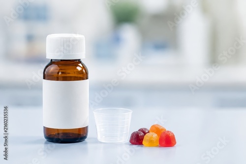 Botella de jarabe y gomitas de frutas en una mesa de laboratorio